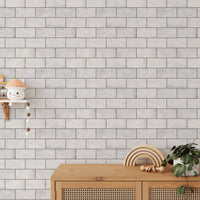 Textured white brick wallpaper behind a wooden sideboard and nursery decor.