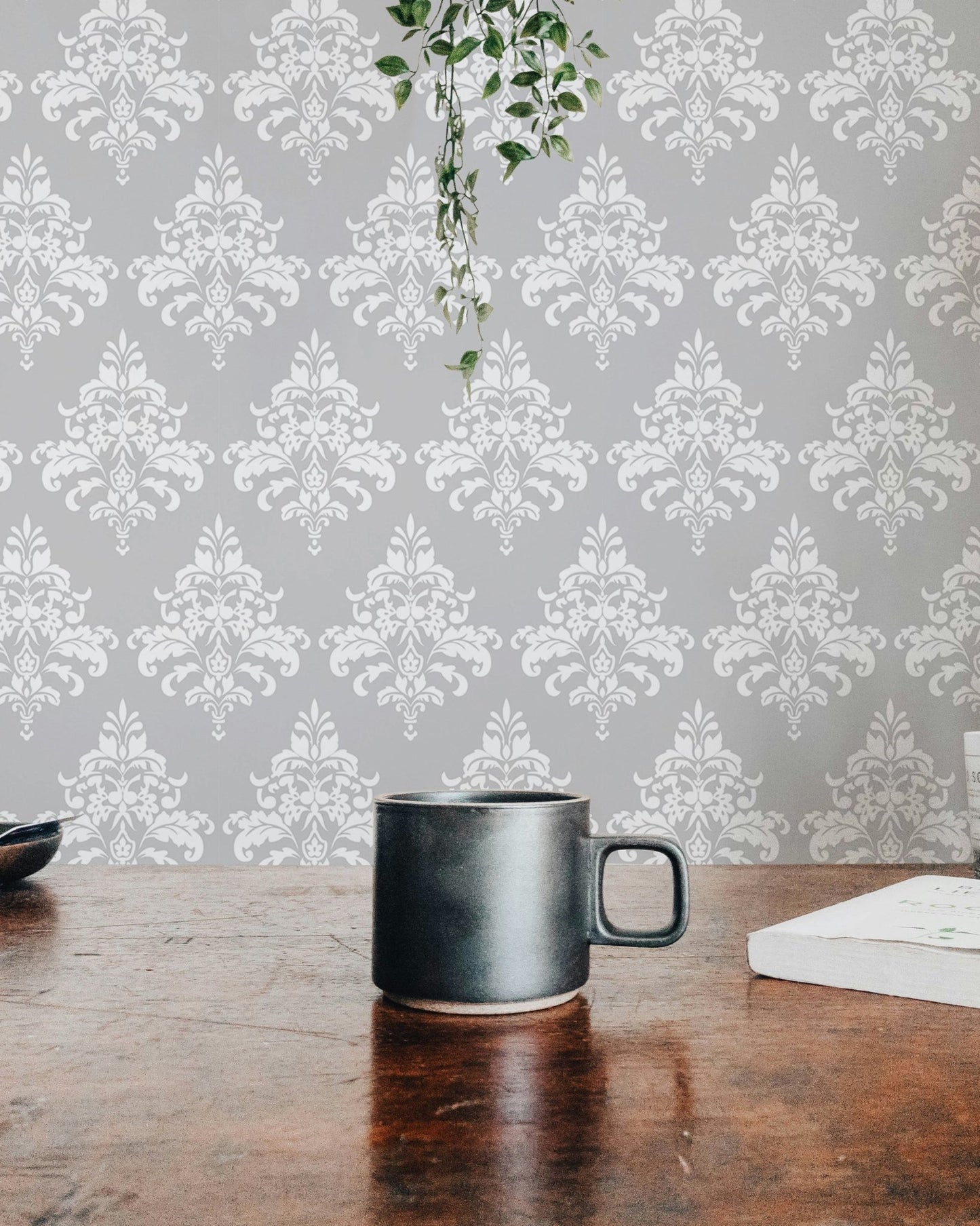 Grey damask pattern wallpaper on a dining room wall behind a dark wood table.