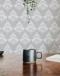 Grey damask pattern wallpaper on a dining room wall behind a dark wood table.