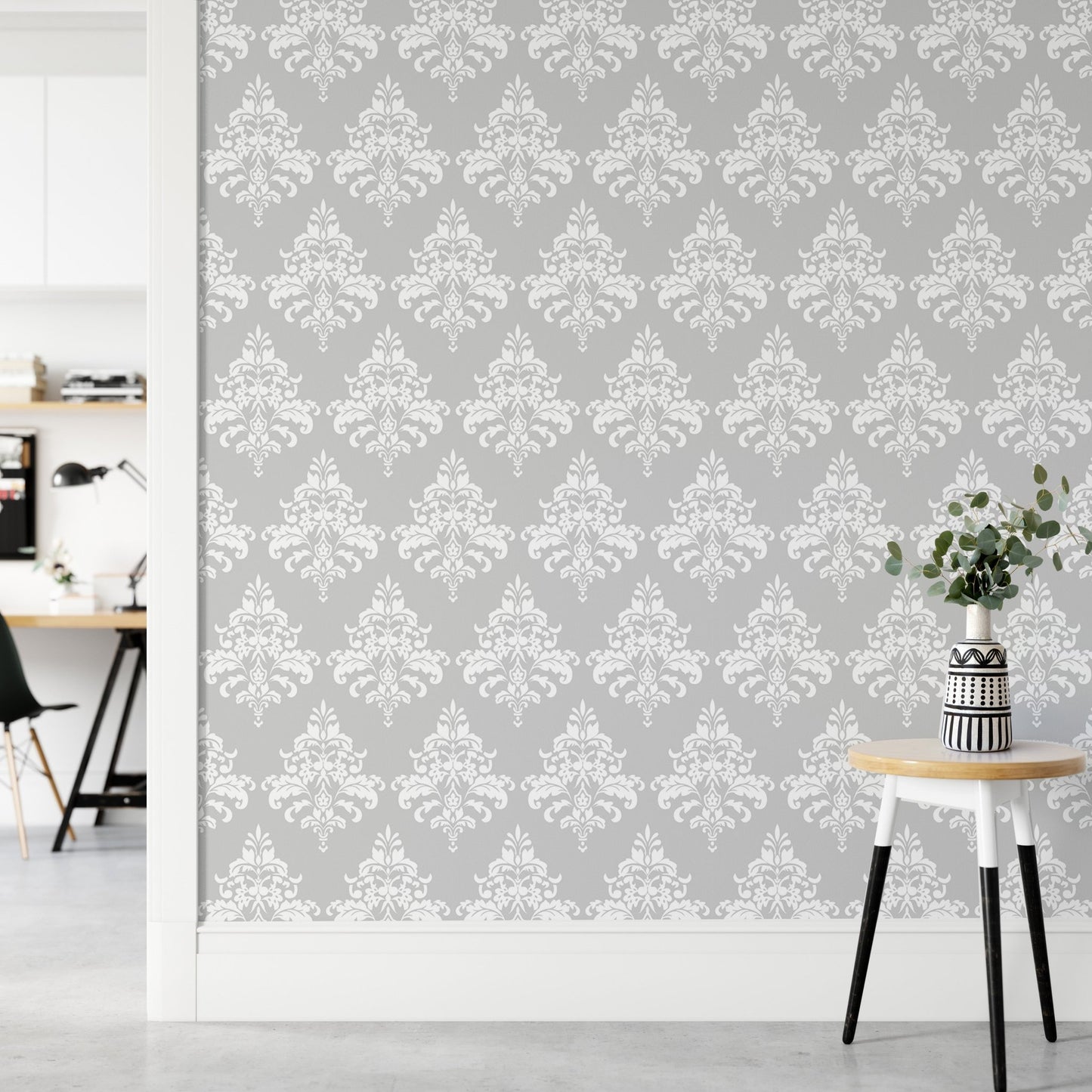 Patterned grey wallpaper next to a white door frame and wooden side table.