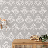 Damask wallpaper behind a wooden sideboard with small decorative items.