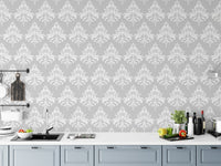 Floral damask wallpaper installed behind a white kitchen counter with grey cabinets.