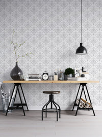 Office workspace with white damask wallpaper behind a black metal desk.