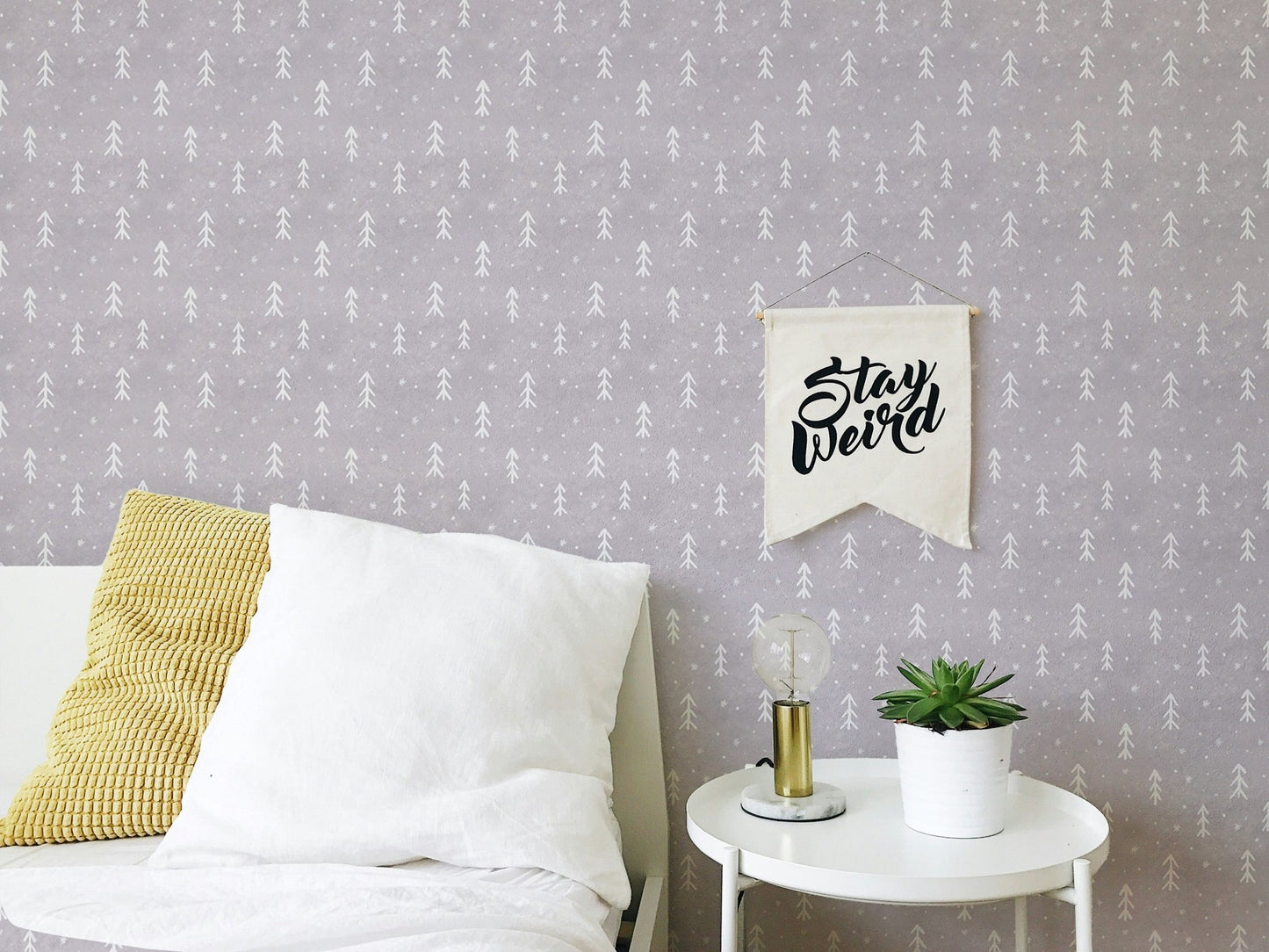 Modern wall mural with white tree patterns next to a bed with yellow pillows.