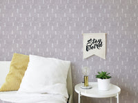 Modern wall mural with white tree patterns next to a bed with yellow pillows.