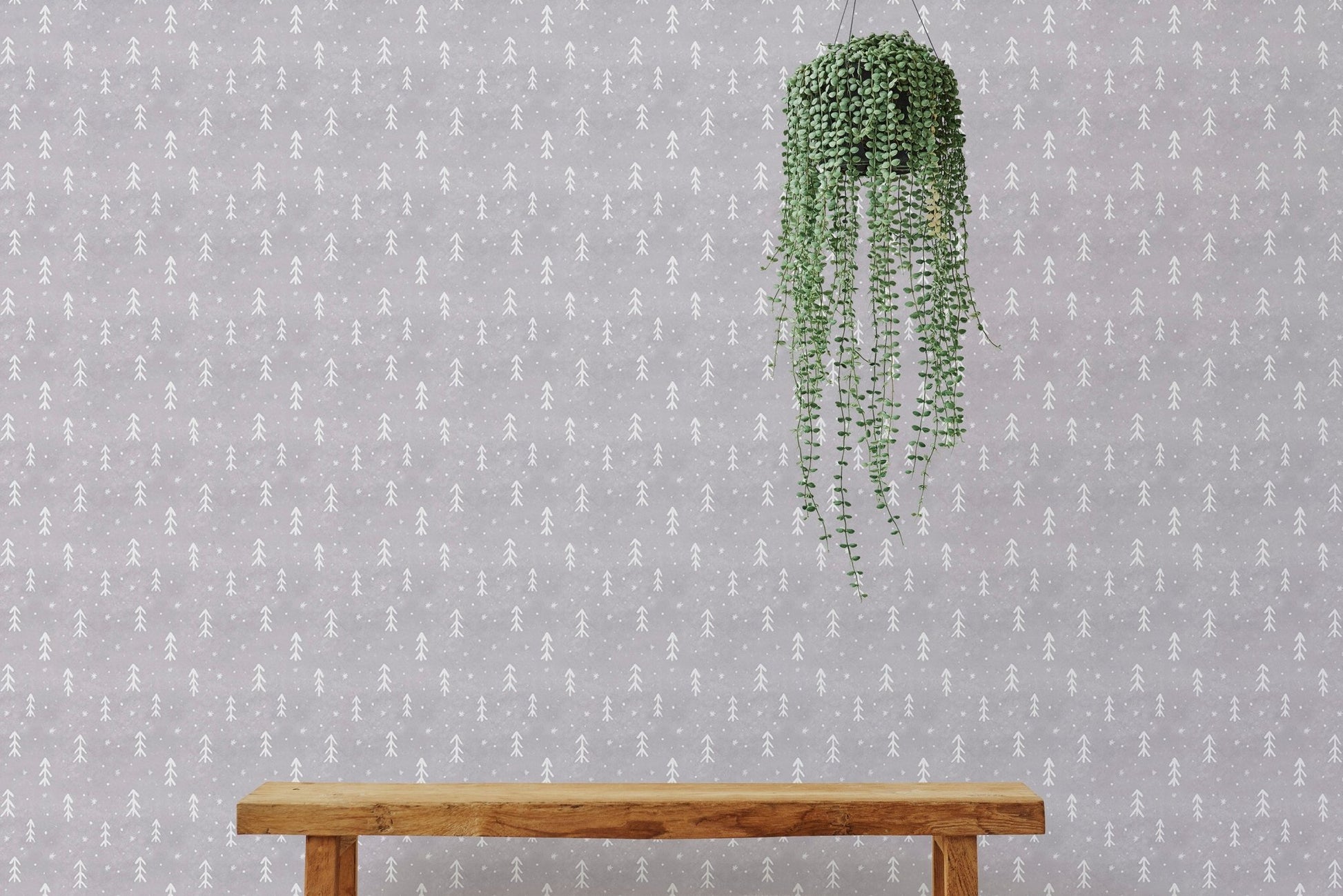 Scandinavian tree wall mural behind a wooden bench and hanging green plant.